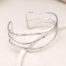 ​A silver-plated bangle comprising three slender, wave-like strands with a hammered texture, designed with an open back for adjustable wear.