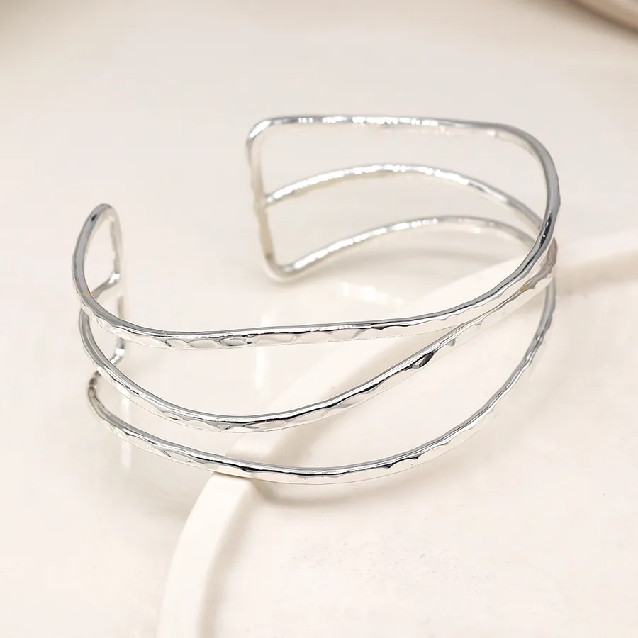 A silver-plated bangle comprising three slender, wave-like strands with a hammered texture, designed with an open back for adjustable wear.